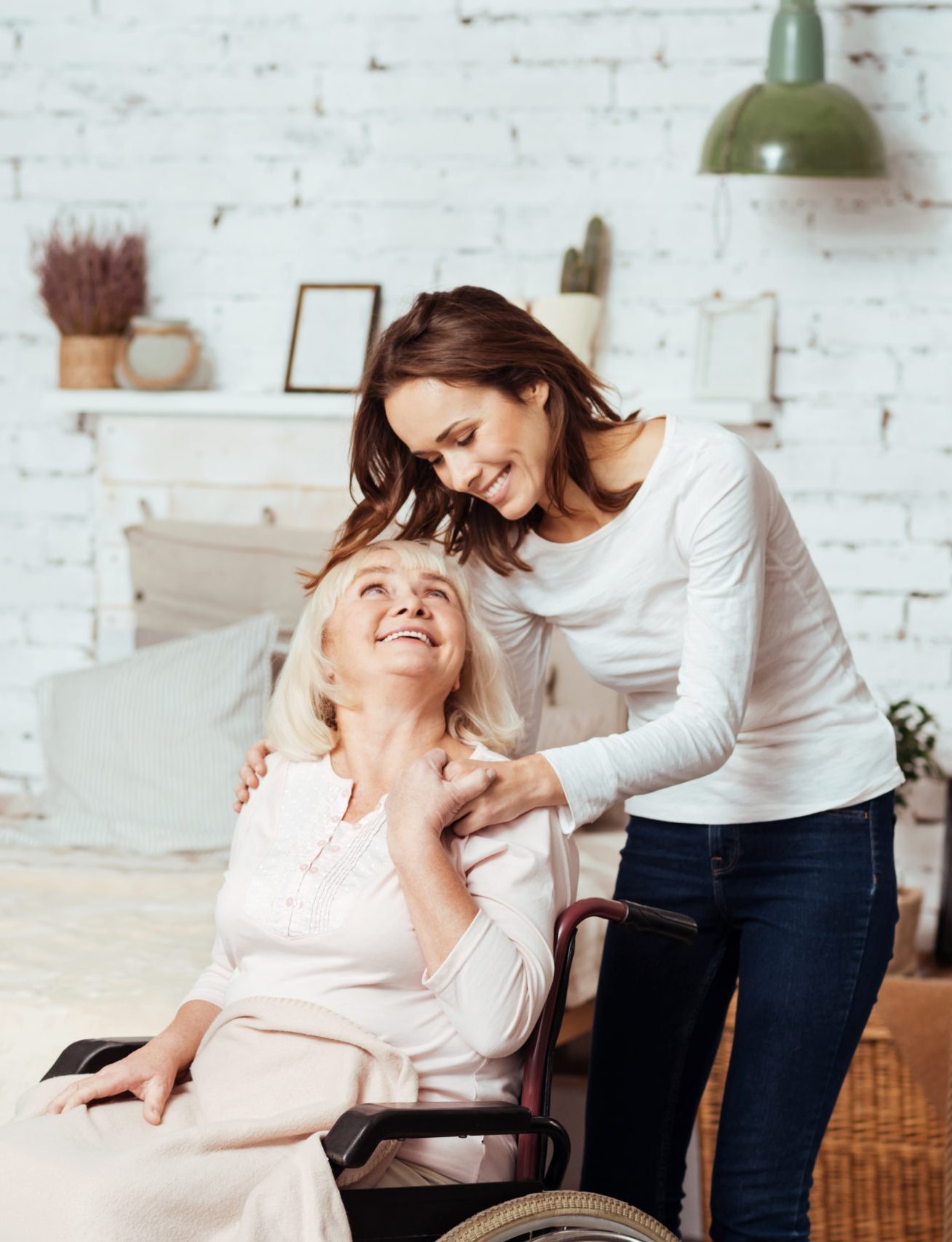 Positive young woman taking care of her grandmother in wheelchair